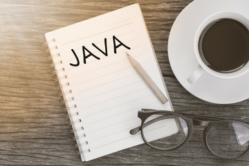 Concept JAVA on notebook with glasses, pencil and coffee cup on