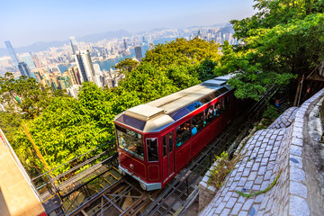 Naklejka na ściany i meble The popular red Peak Tram as he arrives at the terminus of Victoria Peak, the highest peak of Hong Kong island, with panoramic city skyline in background. Sunny day.