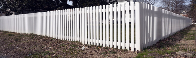 White plastic picket fence on corner lot.
