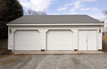 Fototapeta na wymiar Two car garage with door entrance and gravel driveway.