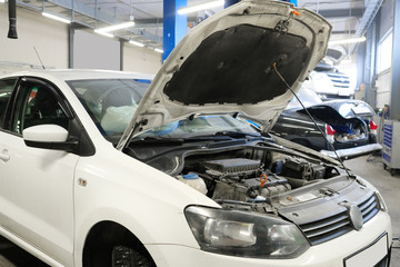 Car with an open hood in a repair station