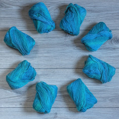 Blue skeins of yarn are lying on a wooden background in a circle shape.