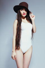 Beautiful girl with long hair in a white body suit and hat