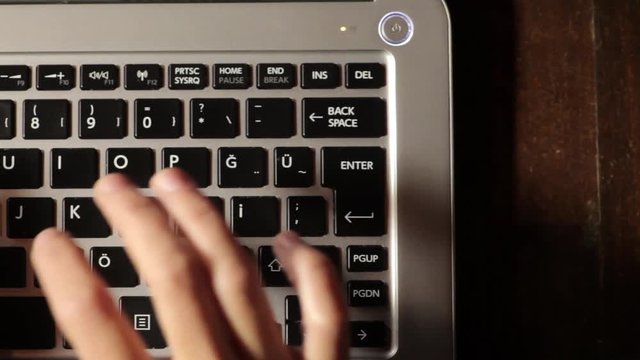 Horizontal panning shot of a woman's hands working on a laptop.