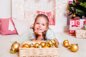 Happy smiling girl with lights and gold Christmas balls and red and white gifts. Christmas.