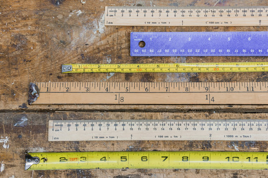 Measuring sticks, rulers, tape measures on workshop table in lin