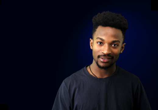 young black man in T-shirt on black and blue background
