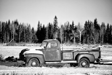 An old vintage truck sitting in a black and white winter landscape