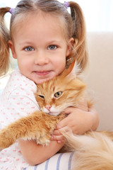 Cute little girl with red cat at home