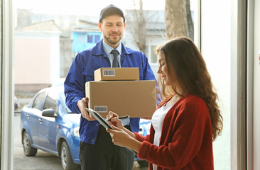 Young woman signing documents after receiving parcels from courier