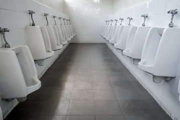 Row of white ceramic urinals men public toilet/restroom.