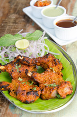 Delicious tandoori chicken starter, served with lime, onion, mint, yoghurt and sauces, on a banana leaf base...