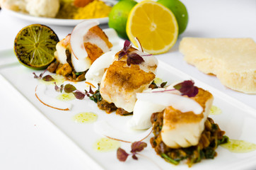 Fresh pan seared, crispy golden cod fish fillet, served on a bed of curried cauliflower, spinach and potato. A beautiful seafood dish.
