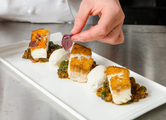 Fresh pan seared, crispy golden cod fish fillet, served on a bed of curried cauliflower, spinach and potato. A beautiful seafood dish.
