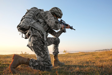 Soldier in camouflage taking aim at military firing range