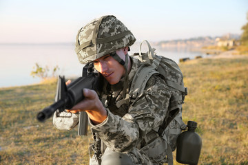 Soldier in camouflage taking aim at military firing range