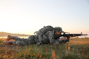 Soldier in camouflage taking aim at military firing range
