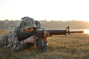 Naklejka premium Soldier in camouflage taking aim at military firing range