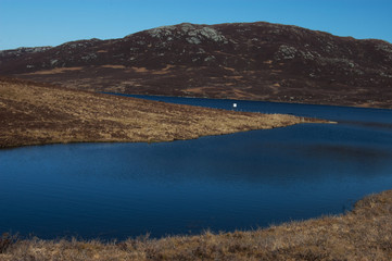 Fototapeta na wymiar Small blue loch in Scottish Highlands on a beautiful sunny day