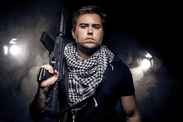 Soldier or mercenary wearing a shemagh with assault rifle, paintball or airsoft gun.  The image...