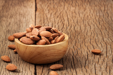 Closeup almonds kernels in wooden bowl with hemp sack on rustic