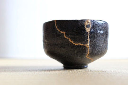 金継ぎされた黒楽の抹茶茶碗を畳の上に置いた和室風景
