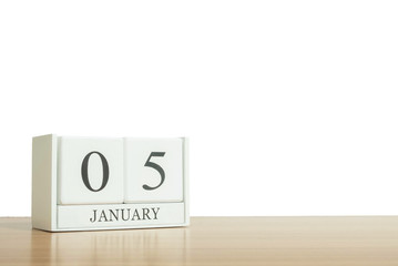 Closeup surface white wooden calendar with black 5 january word on blurred brown wood desk isolated on white background with copy space , selective focus at the calendar