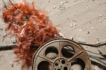 Naklejka premium An old metal rusty cinematography cinema film reel, that has been left in an abandoned cinema amongst concrete debris.