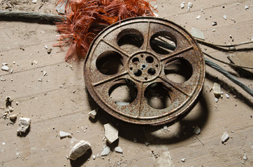 Obraz premium An old metal rusty cinematography cinema film reel, that has been left in an abandoned cinema amongst concrete debris.