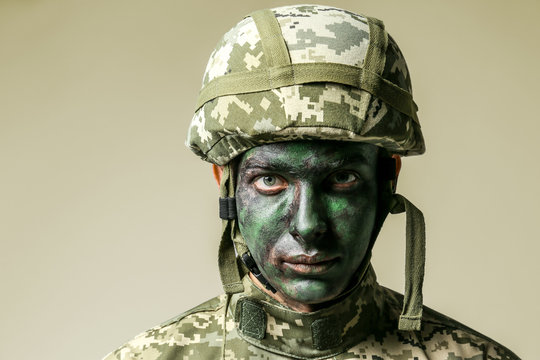 Soldier with face paint on grey background