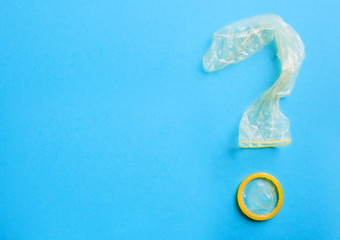 Condom in the shape of question mark on blue background