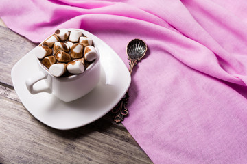 Hot chocolate in white cup with marshmallow on the wooden table. Copy space