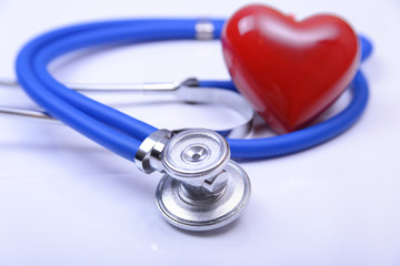 Cardiogram with stethoscope and red heart on table, closeup