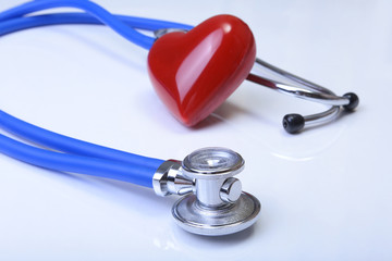 Cardiogram with stethoscope and red heart on table, closeup