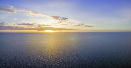 Beautiful glowing yellow-purple sunset over ocean waters with tiny ships in the distance