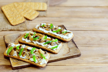 Diet snack with roasted mushrooms and fresh green bell pepper on a board and on a wooden background with copy space for text. Quick and healthy vegetarian snack. Homemade cuisine. Closeup