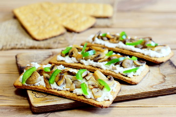 Tasty appetizer with fried mushrooms and fresh green bell pepper on a wooden board. Easy and hearty vegetarian snack. Homemade recipe. Closeup