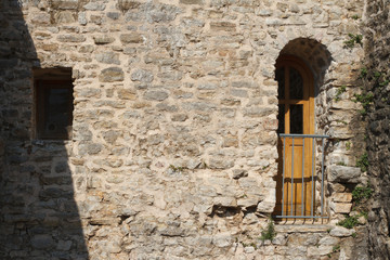 The narrow old door and a window in the wall of the citadel of Budva