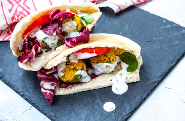 Falafel and vegetables in pita bread with a classic yogurt sauce. Concrete background.