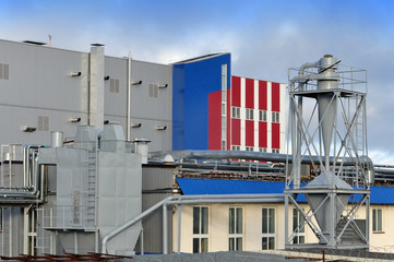 Facade of a modern industrial building with a variety of pipes and installations.