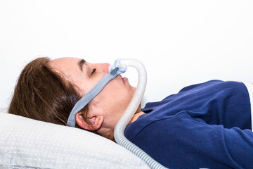 Woman sleeping on her back with CPAP, sleep apnea treatment. Profile portrait taken from the side. © Pebo