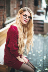 Obraz premium Blonde girl with glasses, smiling in a burgundy sweater, snow, winter