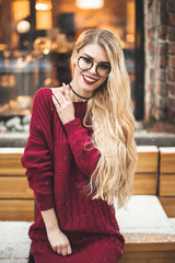 Blonde girl with glasses, smiling in a burgundy sweater, snow, winter