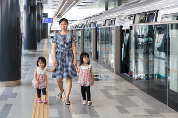 Asian Chinese mother and daughters waiting for transit at statio