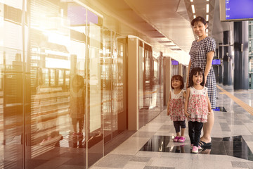 Asian Chinese mother and daughters waiting for transit at statio