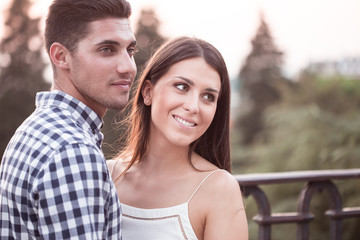 Obraz premium Smiling young and beautiful couple hugging at sunset