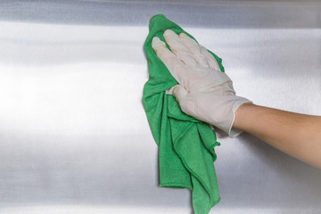 Hand in protective glove with rag cleaning kitchen equipment in the professional kitchen. Stainless steel surface. Early spring cleaning or regular clean up. © fotoduets