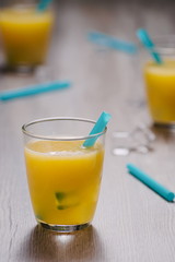 Freshly squeezed orange juice in glass with blue straw and ice c