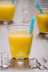 Freshly squeezed orange juice in glass with blue straw and ice c