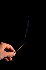 hand with burning incense stick and smoke trail